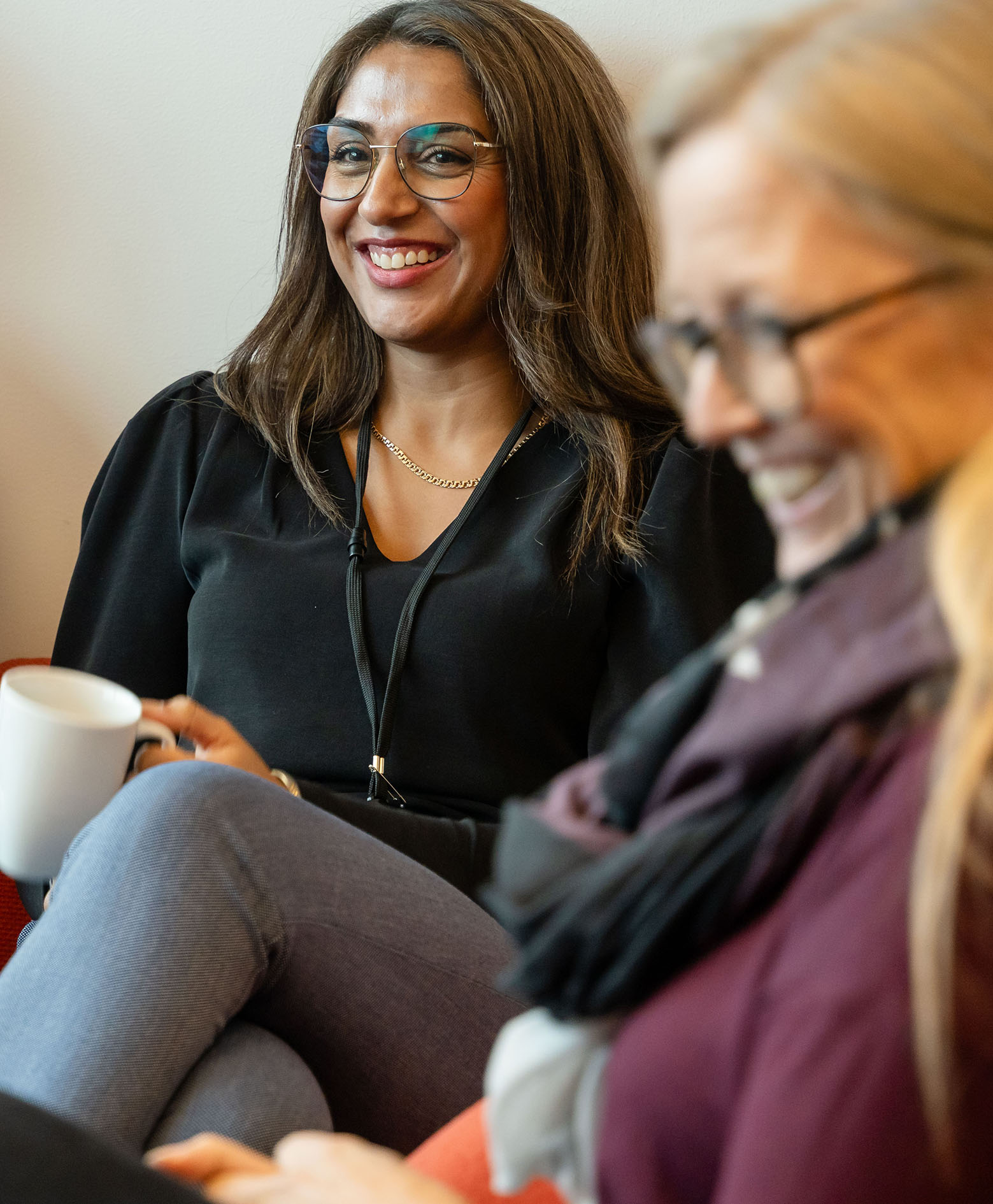 To kvinnelige ansatte hygger seg i sofaen med en kopp kaffe