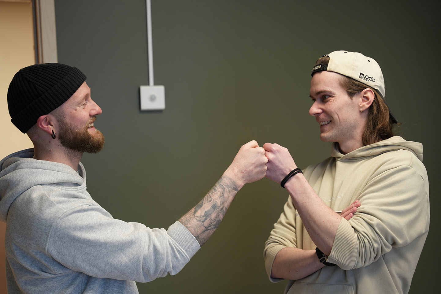 To menn smiler og slår knokene sammen. Foto.