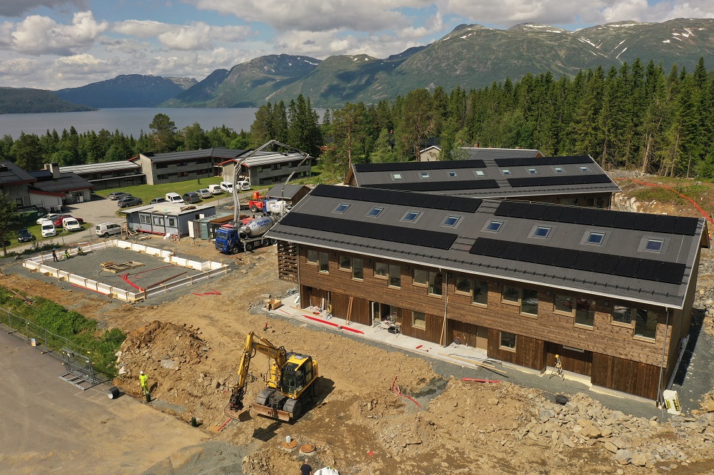 Dronefoto med begge hybelbyggene og skolen i bakgrunnen. Foto.