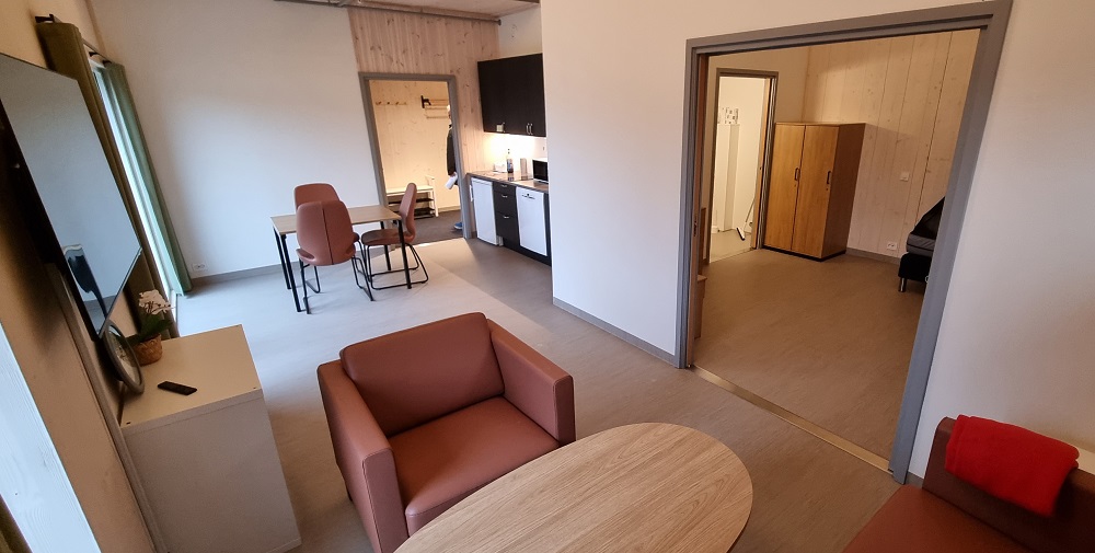 Lys leilegheit med kombinert stove og kjøkken, gang, bad og romsleg soverom med to dører. Foto. 