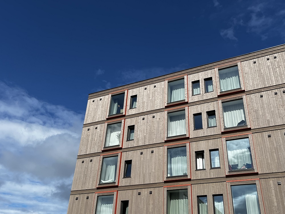 Fasadefoto utsnitt fire øvste etasjar med vindaugsflater mot blå himmel. Foto.