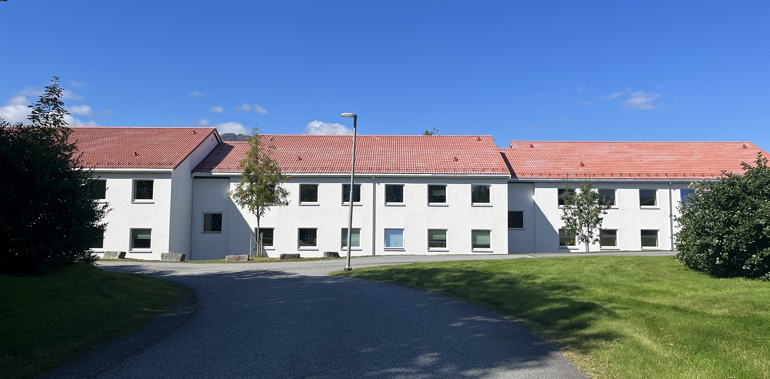 Studentboligbygg i to etasjer med hvitmalt fasade. Foto.