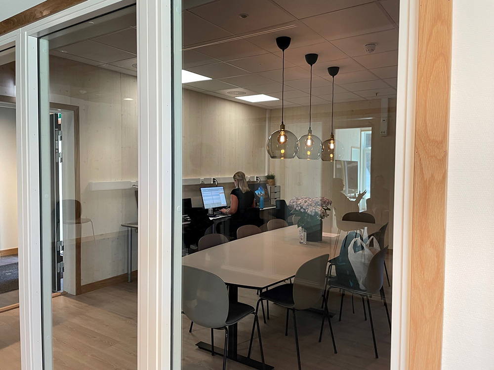 Personalbase med møtebord og PC-stasjoner sett fra innendørsgata. Foto.