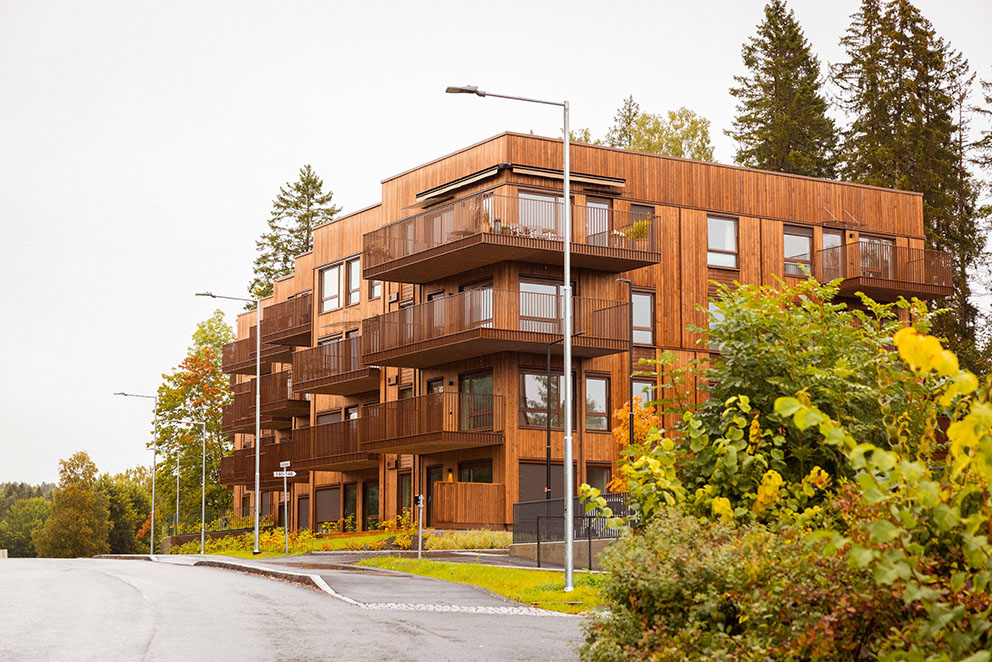 Boligbygg med trekledning og balkonger langs vei og fortau.