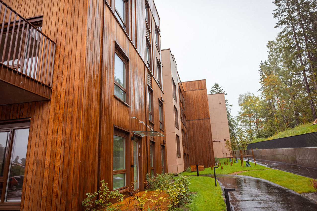 Boligbygg med trekledning og gangvei langs fasaden.