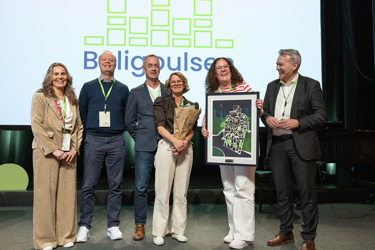 Representanter fra Sarpsborg kommune mottar Boligprisen på en scene. Foto.