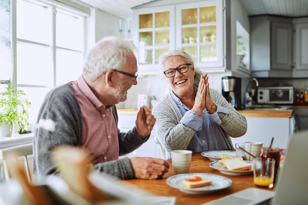 Et eldre ektepar spiser frokost og prater og ler. Foto.
