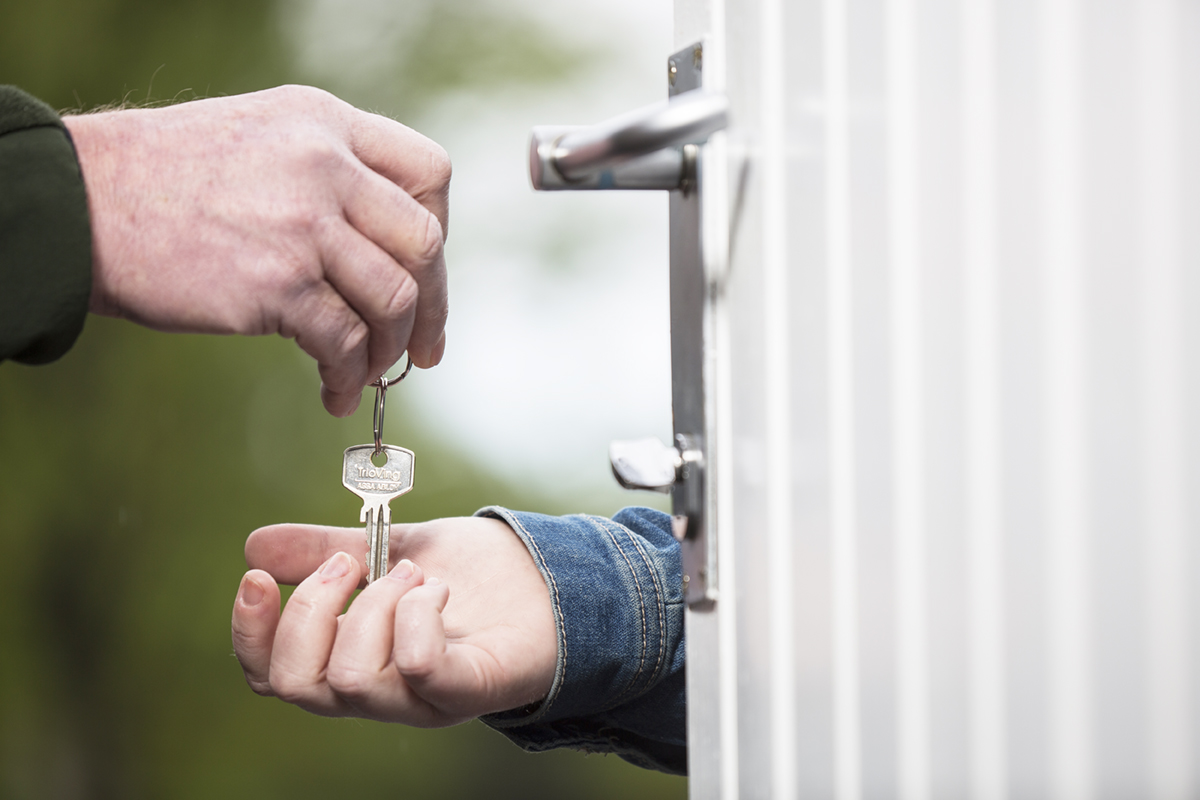 Nærbilde av to hender, der den ene gir den andre en husnøkkel. Foto.